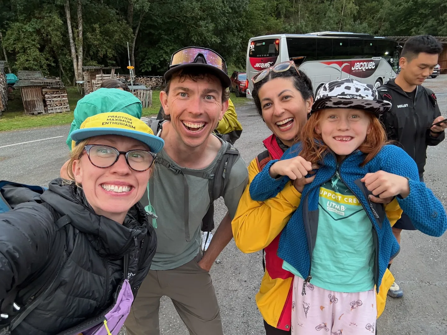 Four members of my support crew crowded into a selfie, grinning, with a coach parked behind them.